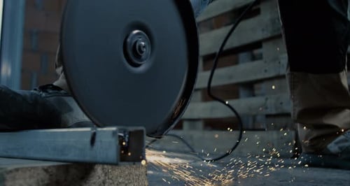 Grinding metal with handheld grinder, sparks shooting in all directions, controlled and steady