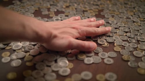 Gently and Intentionally Placing Various Coins on a Surface of a Table During a Casual Setting