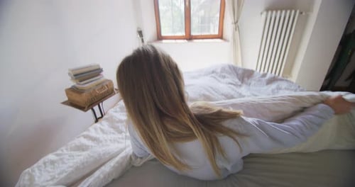 Woman Wakes Up and Stretches in Sunny Bedroom