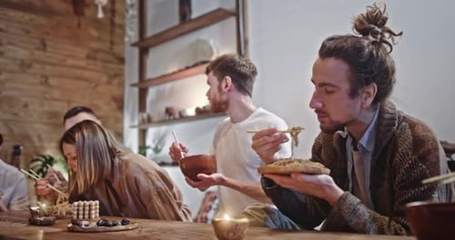 Friends Eating Noodles Together at Rustic Table