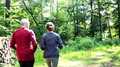 Rear View of Senior Sporty Couple Running in the Forest Outdoors In