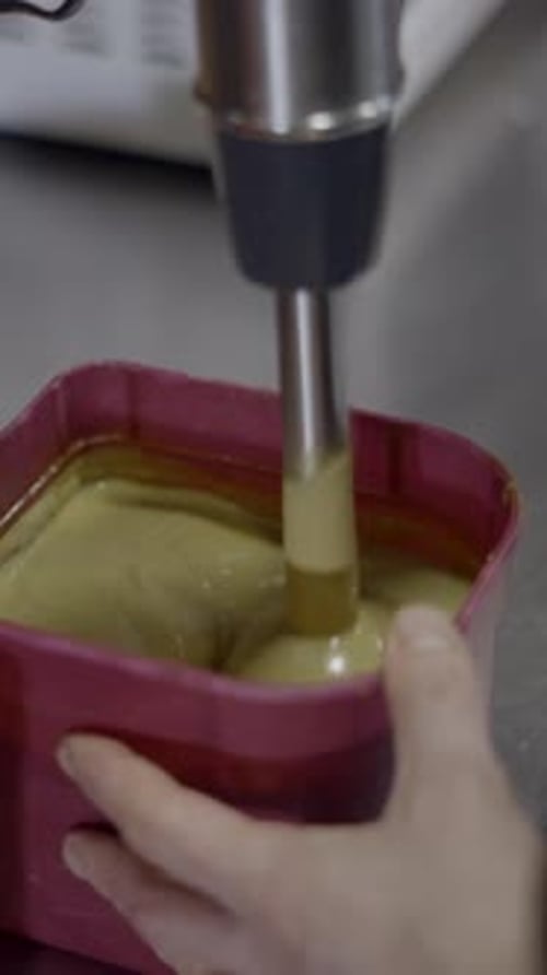Close Side View of Chef Mixing Sauce with Immersion Blender in Kitchen