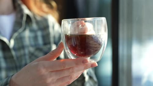 Woman Holding Glass of Dark Beverage Near Window