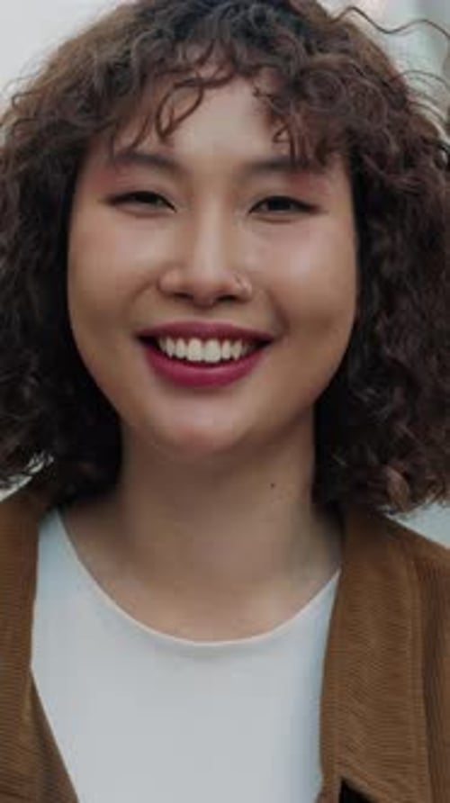 Vertical Video Portrait Of Curly Young Asian Girl Standing Outdoors With Toothy Smile Enjoying