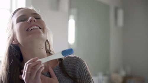 Happy Woman Holding Pregnancy Test in Home Bathroom