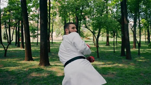 Outdoors in the Park in Sunny Weather Young Karate Guy Dressed in Red Combat Boots and Gloves