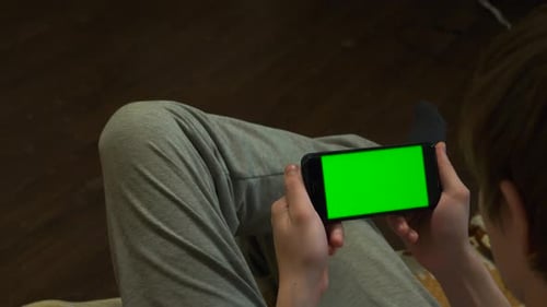 A Person Holding a Smartphone That Features a Green Screen Ideal for Mobile App Displays