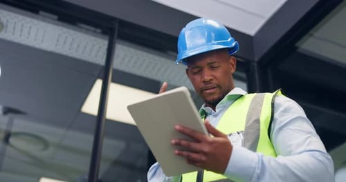 Black man, tablet and engineer on office with typing, notes and low angle for construction planning