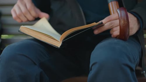 Man Reading Book on Park Bench
