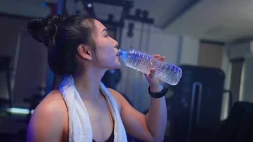 Asian Sportswoman Drinking Water After Gym Workout