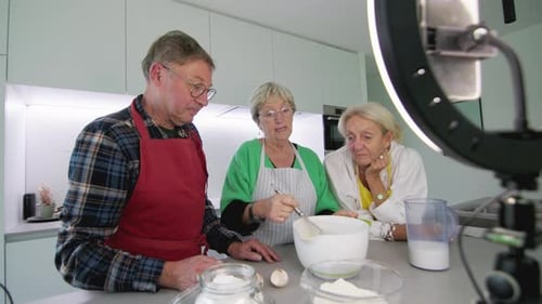 tres personas mayores grabando una clase de cocina en línea