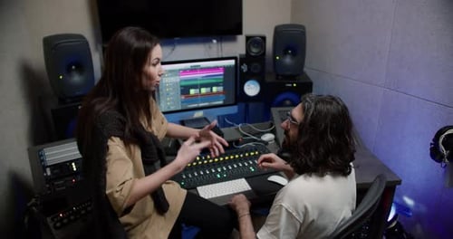 Jeune chanteuse communiquant avec un opérateur sonore et discutant d'une nouvelle composition musicale