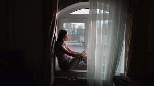 Woman Sits and Contemplates by Bright Window