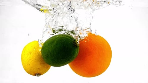 Citrus Fruits Plunge Into Water Creating Bubbles