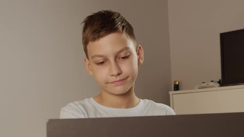 Teen Boy Focused on Laptop Screen at Home