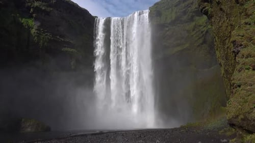 Majestic Skogafoss waterfall cascades down rocky mountain during daytime in Iceland. Surrounded by r