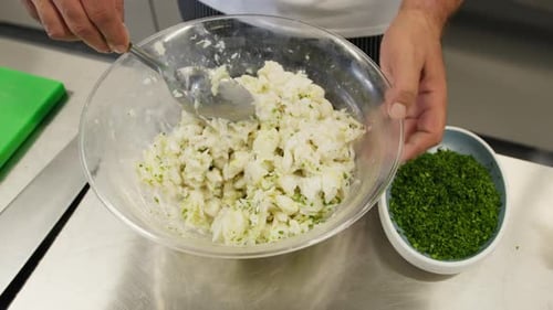 Chef Mixing Fish with Herbs in Bowl