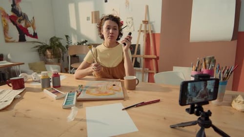 Artista femenina grabando un tutorial de pintura en un teléfono inteligente