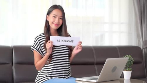 Smiling Woman Holding a Stayhome Sign at Home