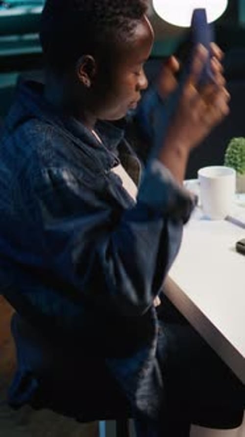 Young Adult Works at Desk with Headphones at Night