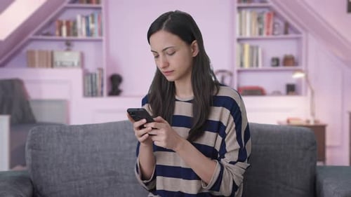 Woman Using Phone While Sitting on Couch Indoors