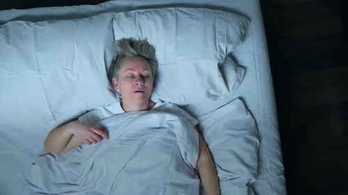 Un homme endormi ronfle dans son lit, vue de dessus