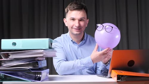 Office Worker Showing Balloon with Glasses at Desk