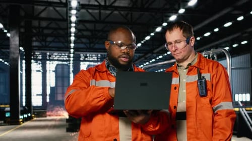 Diverse Operators Use Laptop to Coordinate Production Activity on Factory Floor