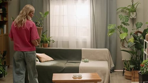 Niña trae nuevas plantas de interior para jardinería interior en una sala de estar verde