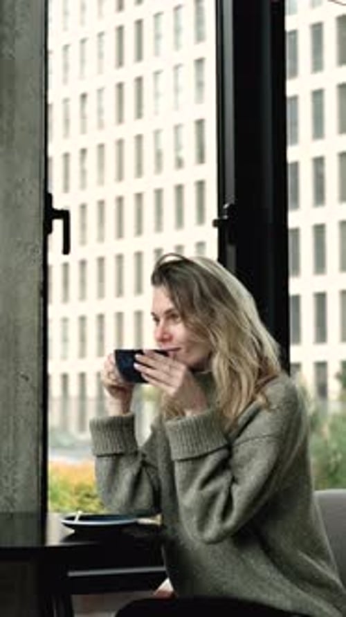 charming woman drinking coffee in coffee shop with house in background