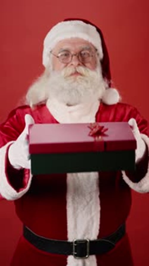 Cheerful Santa Holding out Xmas Present in Red Box with Ribbon