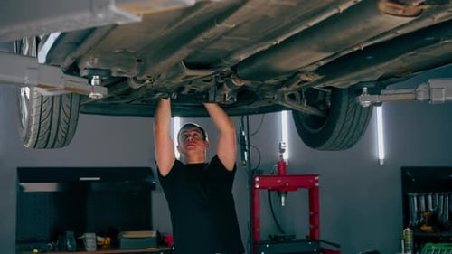 un mécanicien automobile d'une station-service vérifie qu'une voiture est soulevée sur un ascenseur et résout les problèmes liés à un