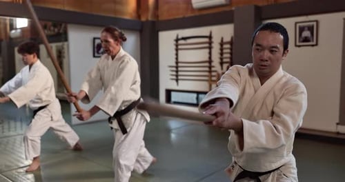 Adults Practicing Martial Arts with Wooden Sticks Indoors