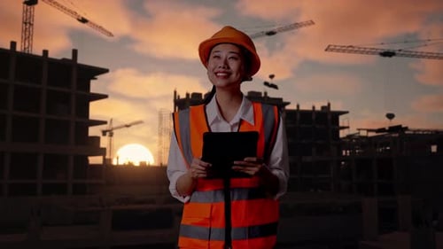 Asian Female Engineer Looking At The Tablet In Her Hand At Building Site