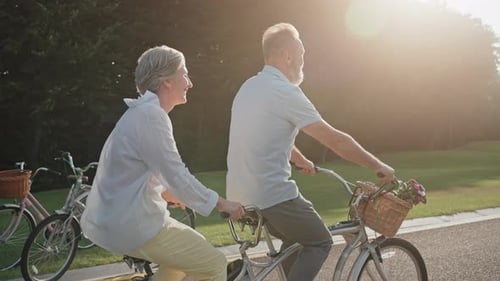 Mature Partners Riding Tandem Bike on Straight Paved Road
