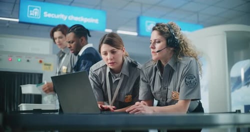 Focused Airport Security Workers Using Laptop