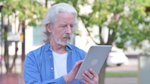 Senior Man Using Tablet Outdoors During Daytime