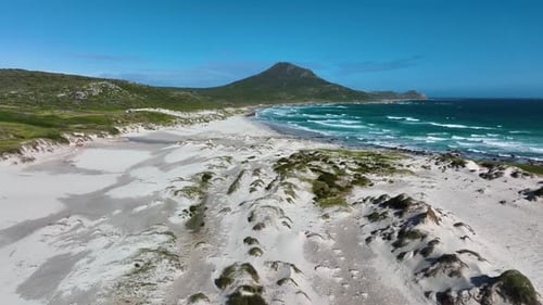 Low flight above rugged sandy beach towards distant Cape of good hope mountain