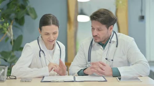 Male and Female Doctor Discussing Patient in Clinic