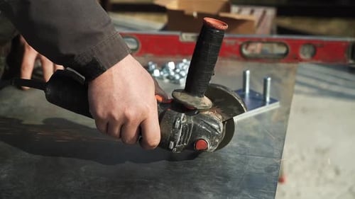 Worker cutting metal tube using an Angle Grinder. Bright sparks and flashes