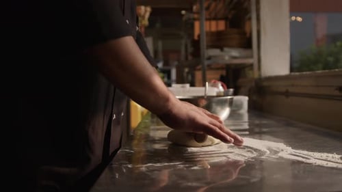 Chef rolling dough on a restaurant kitchen table, handheld shot on isolated action