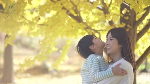 Happy Mother and Child Smiling in Autumn Park