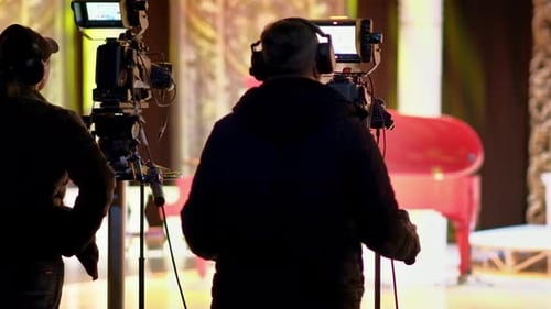 Mann filmt mit professioneller Kamera hinter den Kulissen eines Fernsehers