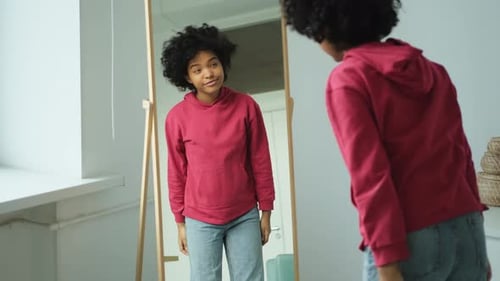 Liebe dich selbst Schöne junge lächelnde Afroamerikanerin tanzt und lockiges Haar berührt und genießt
