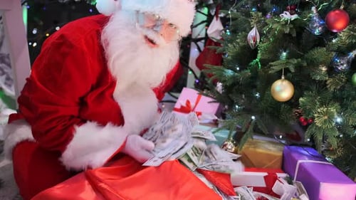 Santa Claus takes a bunch of cash dollars out of a red gift bag to put under the Christmas tree