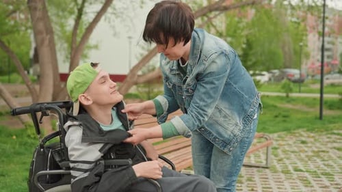 Gentle Aid Provided Compassionate Support In Park Assisting Young Man With Wheelchair Trustfully