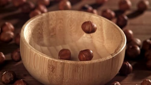 Des noisettes tombent dans un bol en bois, filmées par une caméra haute vitesse à 1000 images par seconde