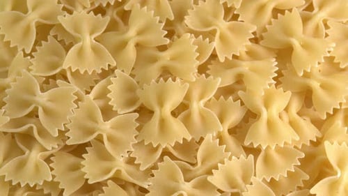 Authentic italian dry pasta farfalle rotating closeup background top view low light. Raw dried