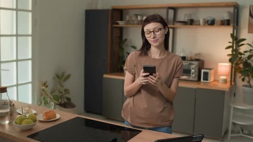 Smiling woman with smartphone in a modern kitchen