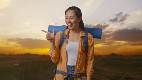 Asian Female Hiker Smiling And Pointing To Side On The Top Of Mountain